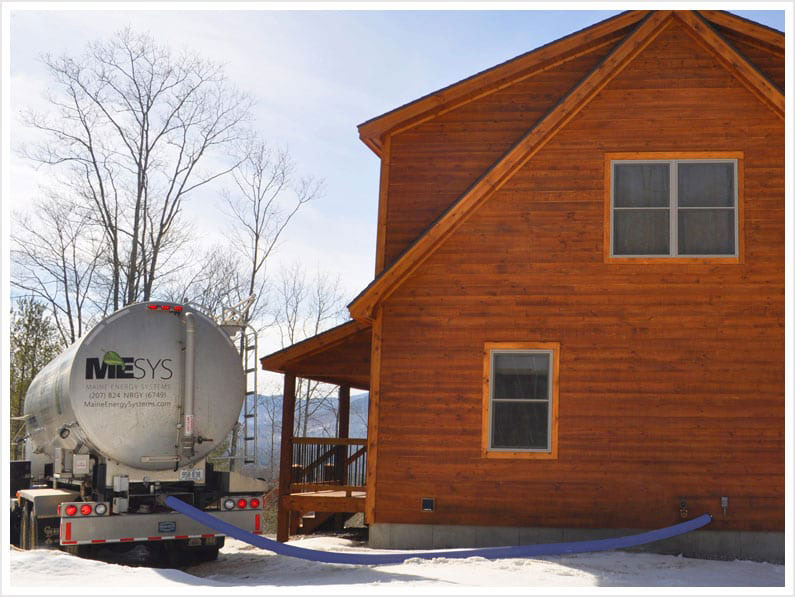 Photo of a pellet delivery truck parked next to a residential home in the winter Maine Pellets
